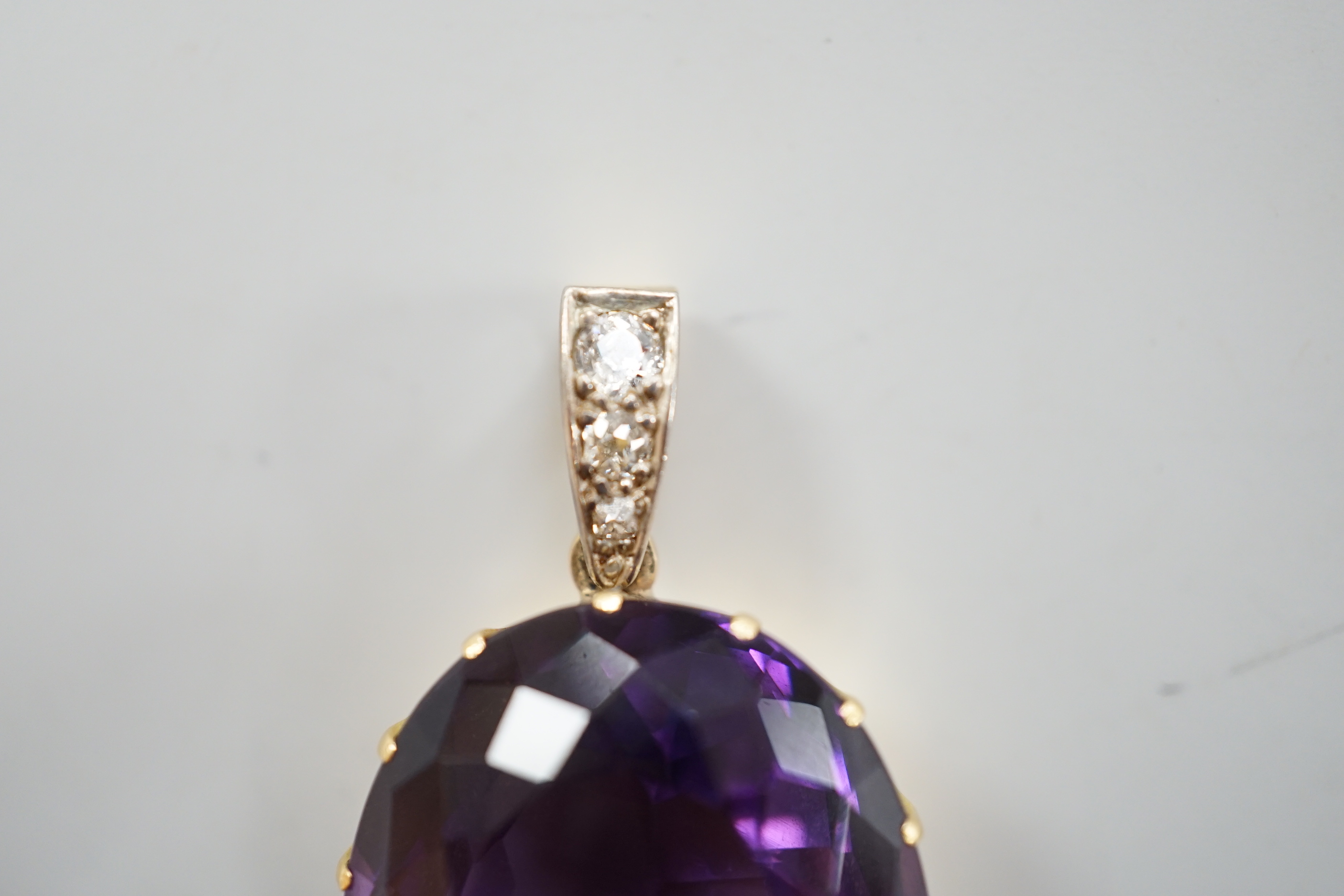 An Edwardian yellow metal, oval cut amethyst and three stone diamond set drop pendant, overall 4cm, gross weight 16.7 grams.